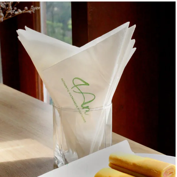 Khăn giấy in logo đặt cạnh ly nước trên bàn quán cafe